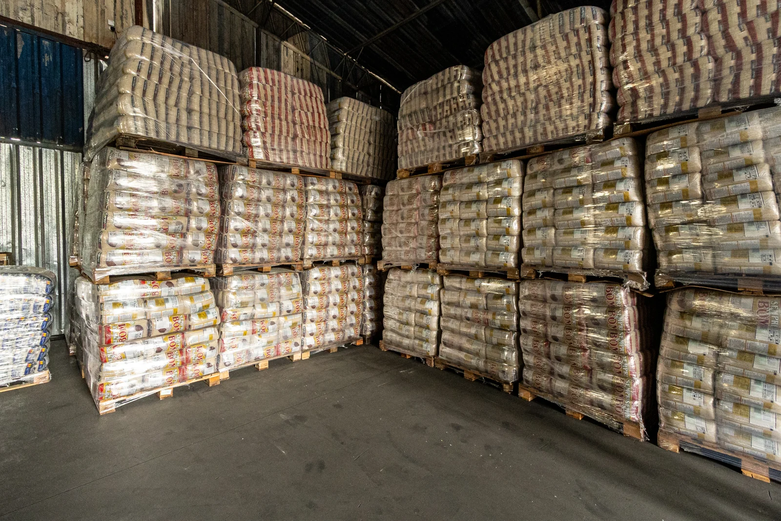 Paletes de alimentos ensacados envoltos em filme plástico, empilhados em galpão