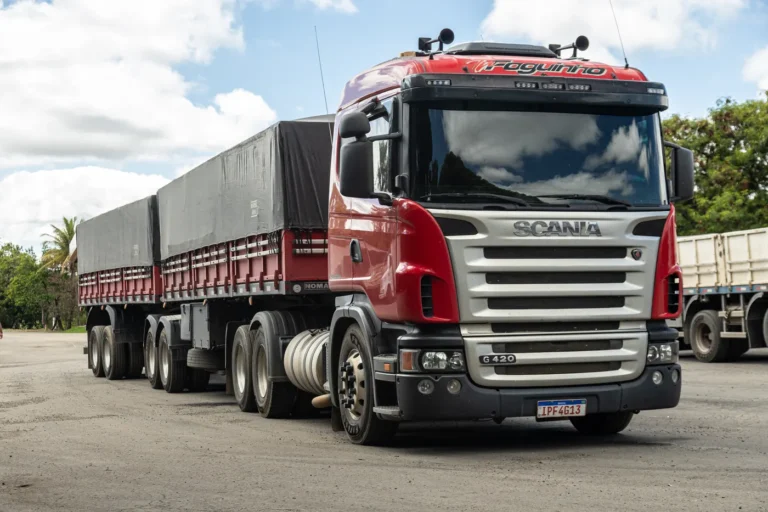 Scania vermelho da frota própria com carga lonada