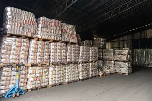 Estoque de fardos paletizados em galpão, com paleteira em primeiro plano