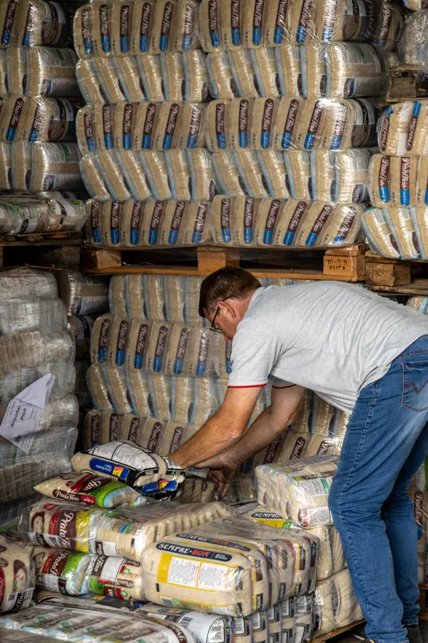 Colaborador da Foguinho organizando fardos de arroz sobre paletes no galpão